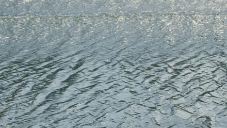 boats pass by and form waves in their wake as they disturb and agitate the surface of the water