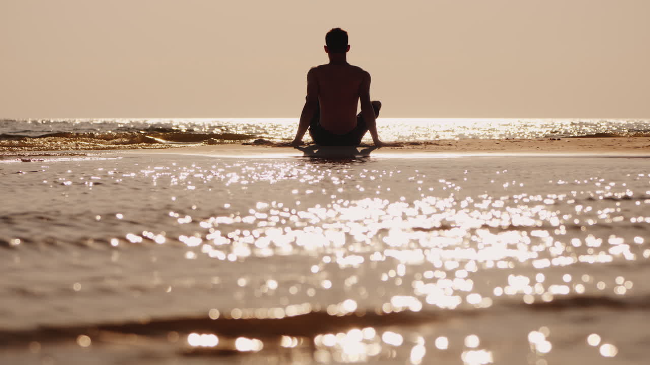 silueta de un joven sentado en una pequeña isla de arena