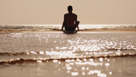 silhouette of a young man sitting on a small sand island