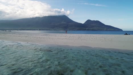 Volando-Más-Allá-De-Una-Linda-Mujer-Rubia-Parada-Sola-En-La-Playa-De-La-Isla-Blanca,-Camiguin