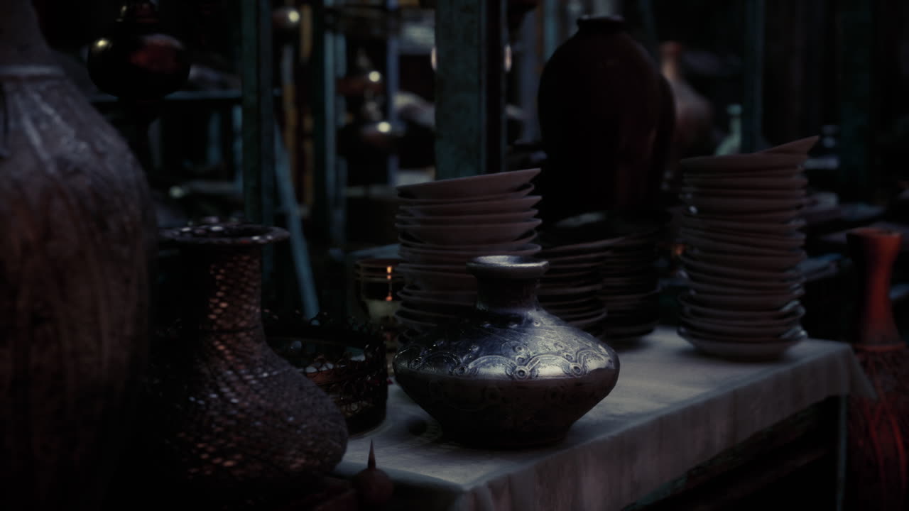 Antique pottery and plates displayed in a dimly lit market setting