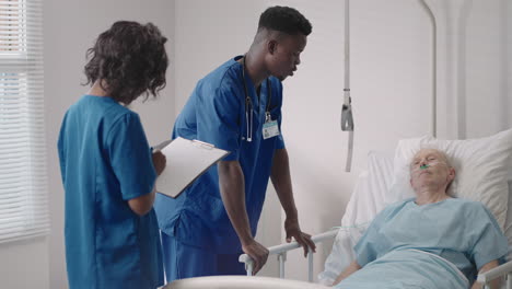 senior patient on bed talking to 2 african american doctor in hospital room health care and insurance concept. doctor comforting elderly patient in hospital bed or counsel diagnosis health.