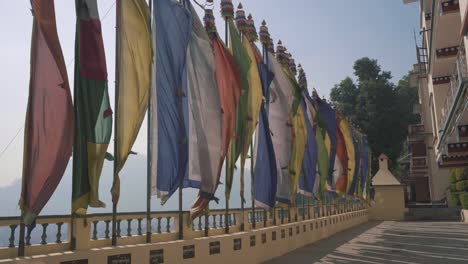 colorful flags waving in the air in front of triten norbutse monastery in kathmandu, nepal on a bright foggy day - panning shot