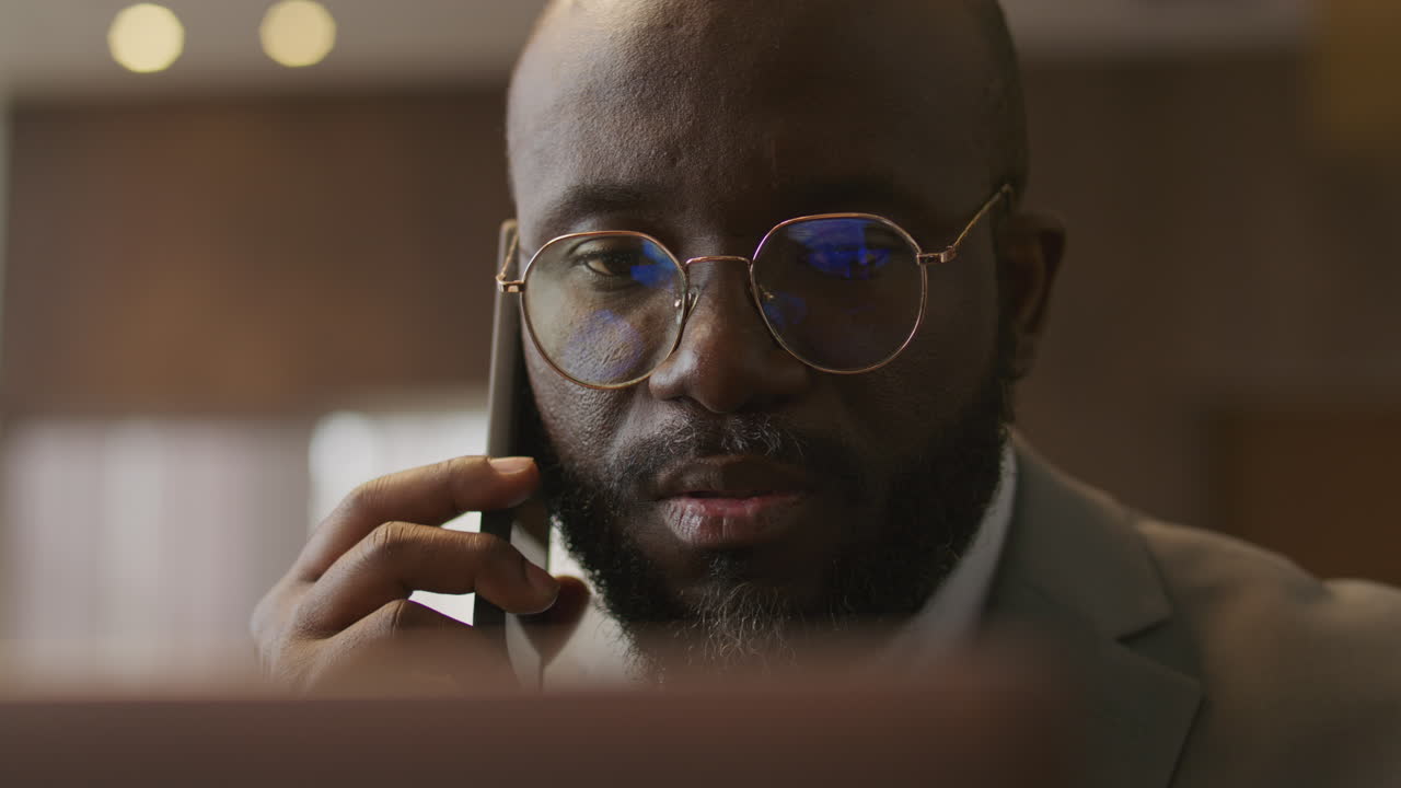 African American Businessman Having Phone Conversation and Working on Laptop