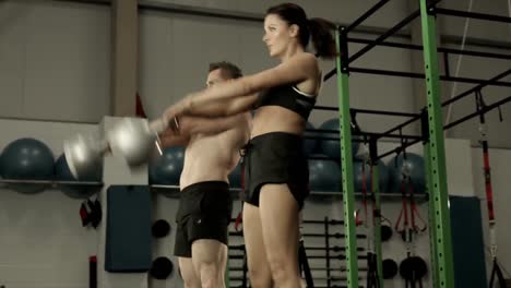 pareja en forma en cuclillas con kettlebells