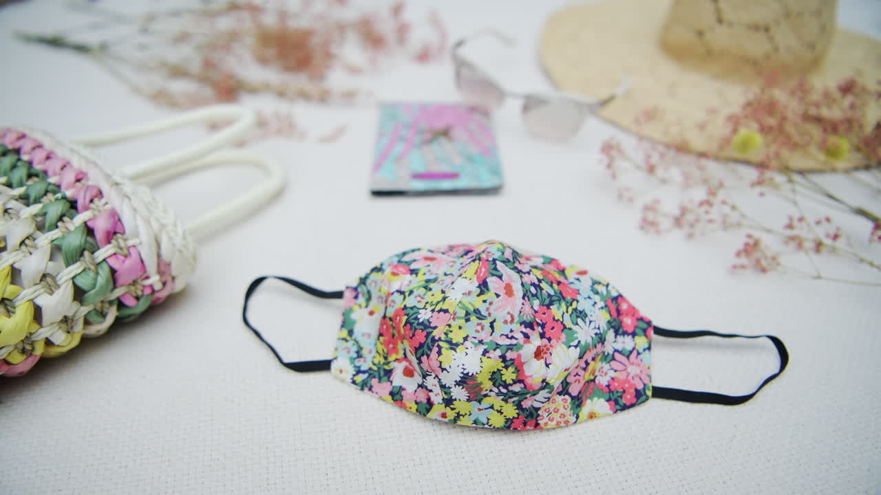Tight shot of traveling items on white surface. Face mask, hat, bag