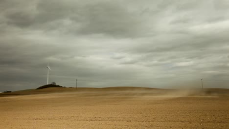 una turbina eólica blanca de tres palas en un campo marrón claro estéril bajo un cielo nublado grisáceo, que exuda un aura desolada y solitaria