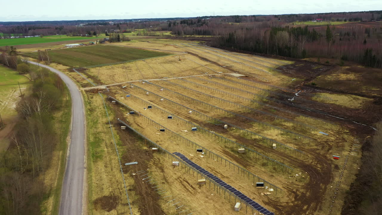 Approaching aerial view of solar panel rows in renewable energy farm in construction