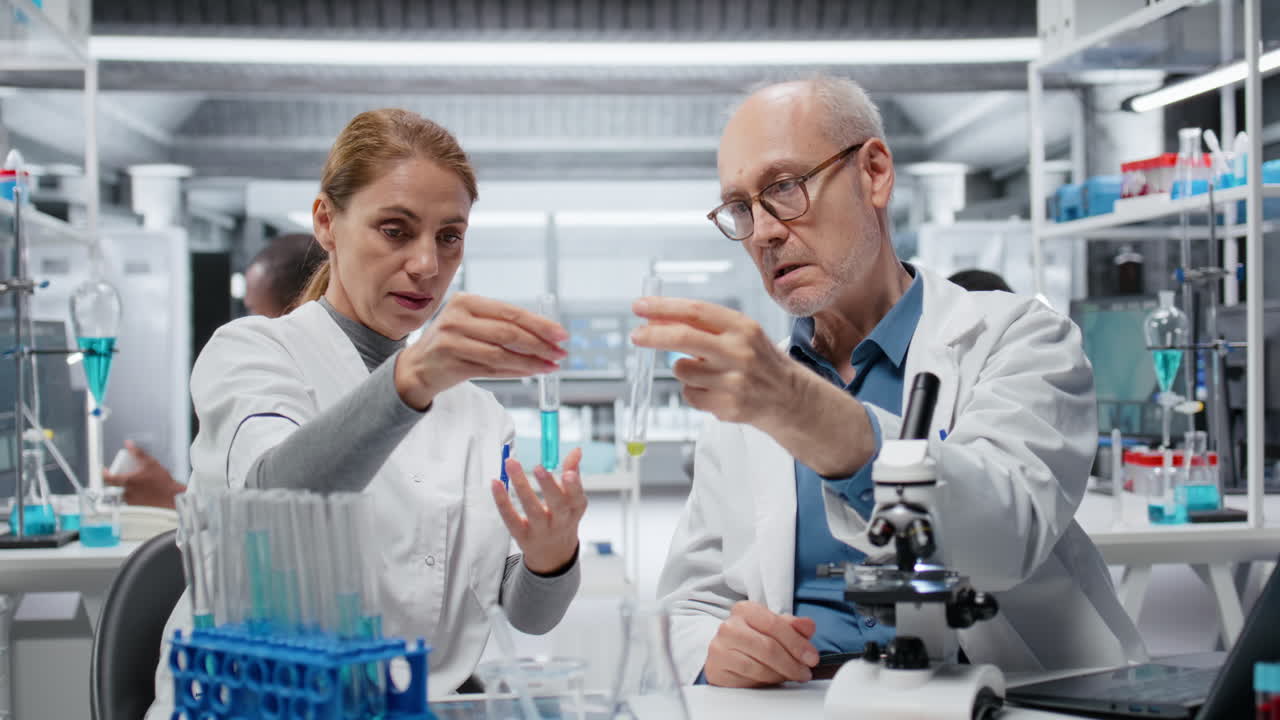 Lab team leader teaching intern to analyze liquid polymer properties