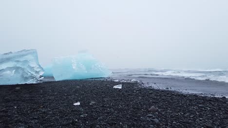 Walking-among-big-pieces-of-glacier-ice-washed-out-on-black-Diamond-beach-in-south-Iceland