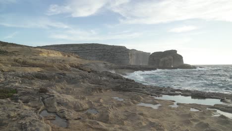 caminar en la playa de piedra cerca de la ventana azul en la isla de gozo durante el invierno