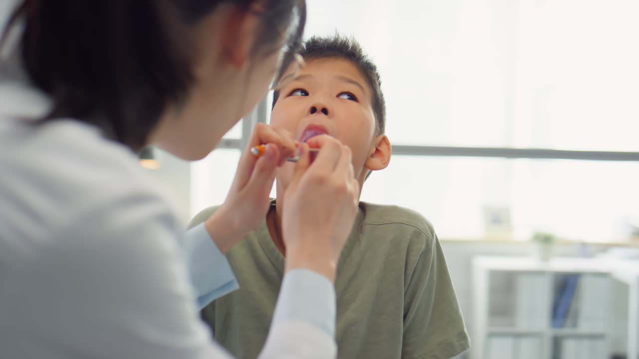 Otolaryngologist Examining Throat of Asian Boy