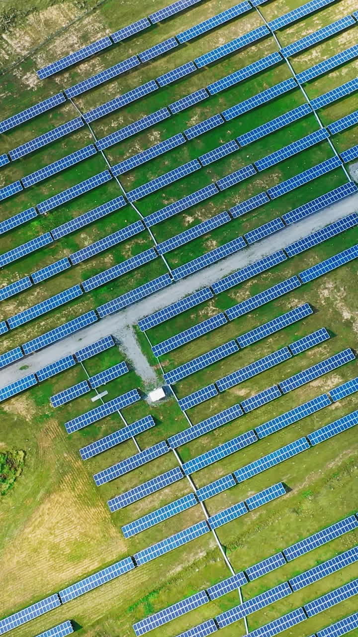 Solar energy panels on the field. Top aerial view on the solar power farm. Renewable green alternative energy concept. Motion camera around. Vertical video