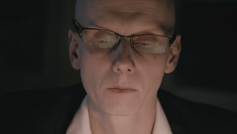 pale bald accountant looks through the tax papers in the weird room at night