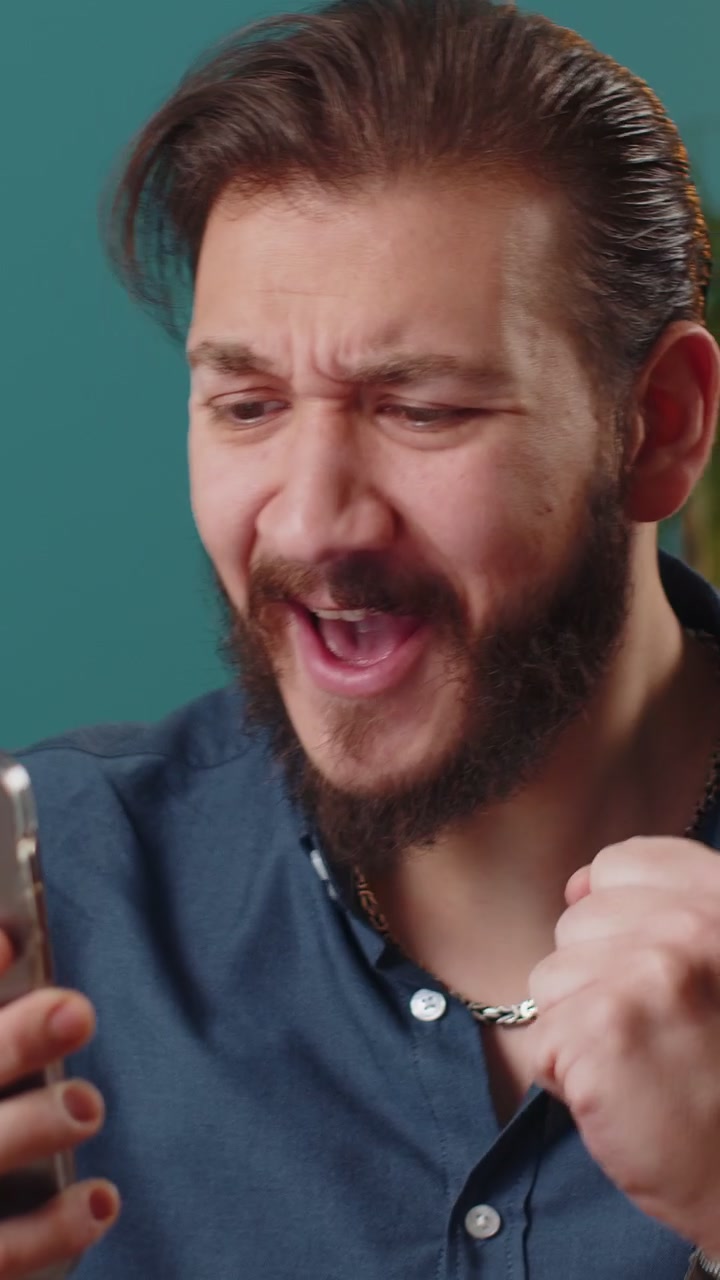 Hombre libanés usando un smartphone, celebrando haber ganado el premio gordo de la lotería, logro de objetivo, buenas noticias, victoria.