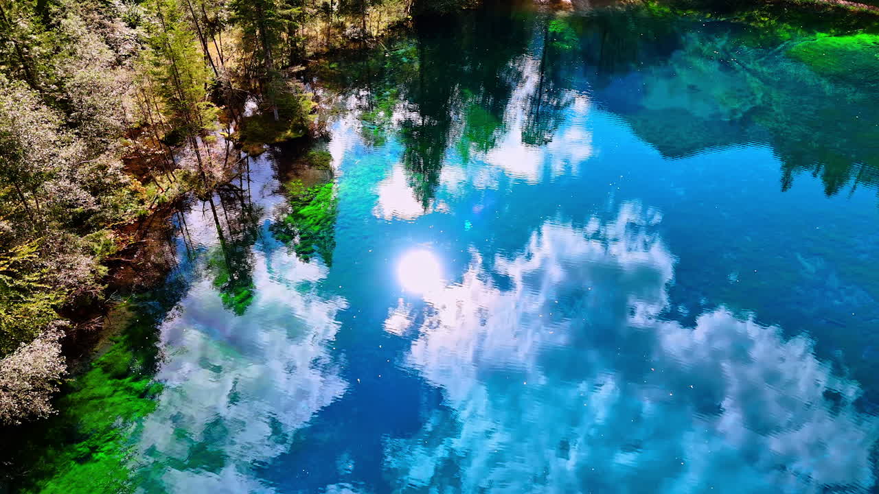 Amazing azure sky with sun and white clouds reflecting in the lake. Aerial perspective on the Christlessee lake, Oberstdorf, Bavarian Alps, Europe.