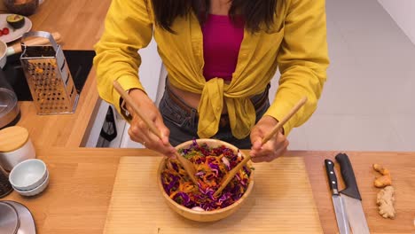 woman mixing colorful vegetable salad in kitchen