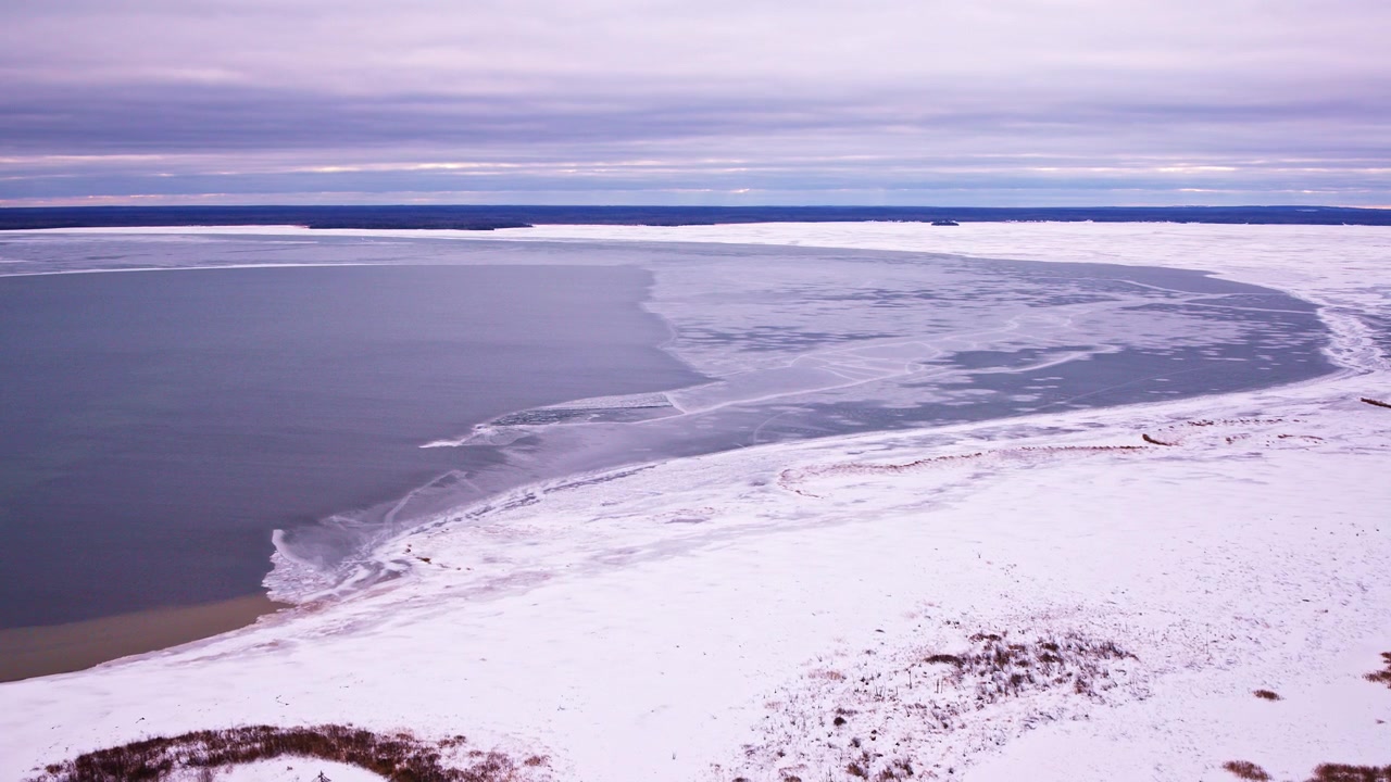 Vinterlandskap fra luften med en delvis frossen bukt på Lake Superior bak en snødekt forgrunn