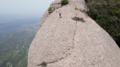 Junge-Frau-Verabschiedet-Sich-Mitten-Im-Nationalpark-Montserrat-Von-Der-Kamera,-Drohne-Entfernt-Sich