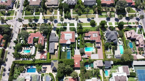 drone shot flying over beautiful west hollywood, los angeles, california neighborhood filled with palm tree lined streets, cars driving and parked, mansions and swimming pools