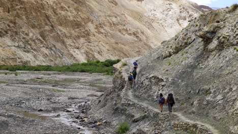 Eine-Gruppe-Von-Touristen,-Die-Mit-Rucksäcken-Auf-Einer-Unbefestigten-Straße-Im-Markha-tal-Wandern