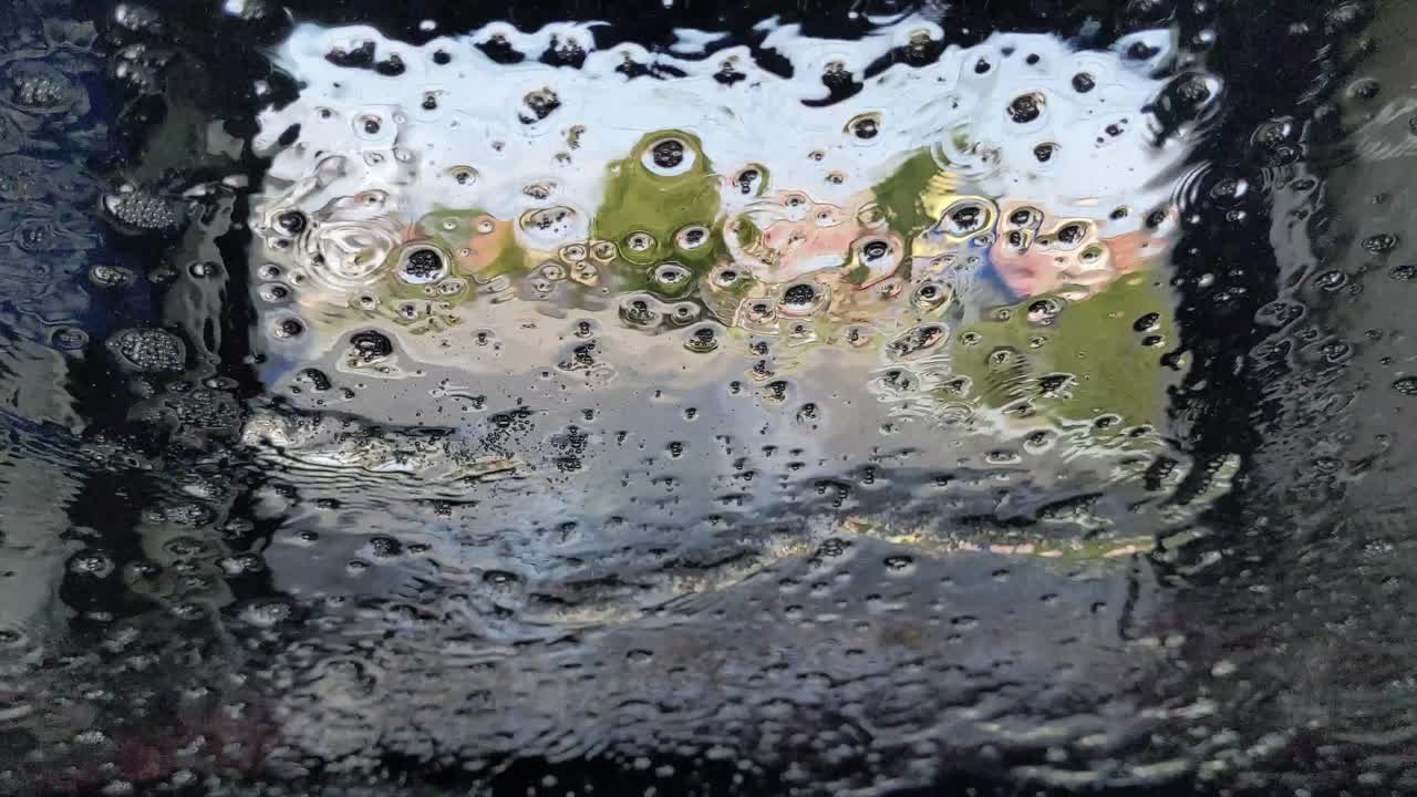 깨끗한 물과 왁스 광택이 터널 세차장을 통과하면서 자동차 앞 유리에서 떨어져 나옵니다.