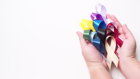 Male-hand-holding-various-colored-ribbons-on-white-background