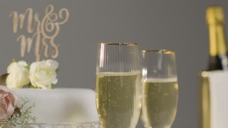 wedding cake with glasses of champagne against grey studio background at wedding reception 4