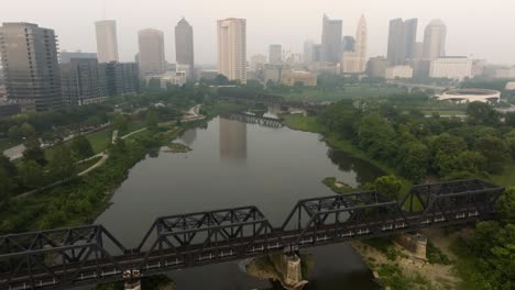 Aerial-view-of-Columbus-Ohio-skyline-with-Scioto-River-and-bridges-for-trains-on-a-foggy-smoky-day