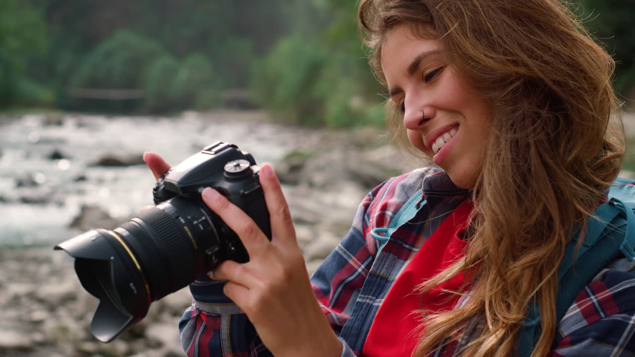 Girl holding photo camera in hands. Photographer looking pictures on camera