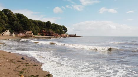 Dysart-Strand-Mit-Sand-Und-Wellen-Im-Vordergrund-Und-Mauern-Und-Türmchen-Im-Hintergrund