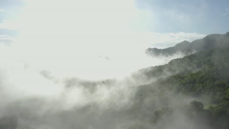 forward drone shot flying through the clouds revealing the morning sun in the mountain ranges of western ghats in india