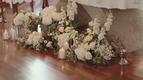 white floral arrangements and glass candles placed at altar floor of traditional church