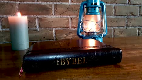 closed bible on table with candle and oil lamp slides