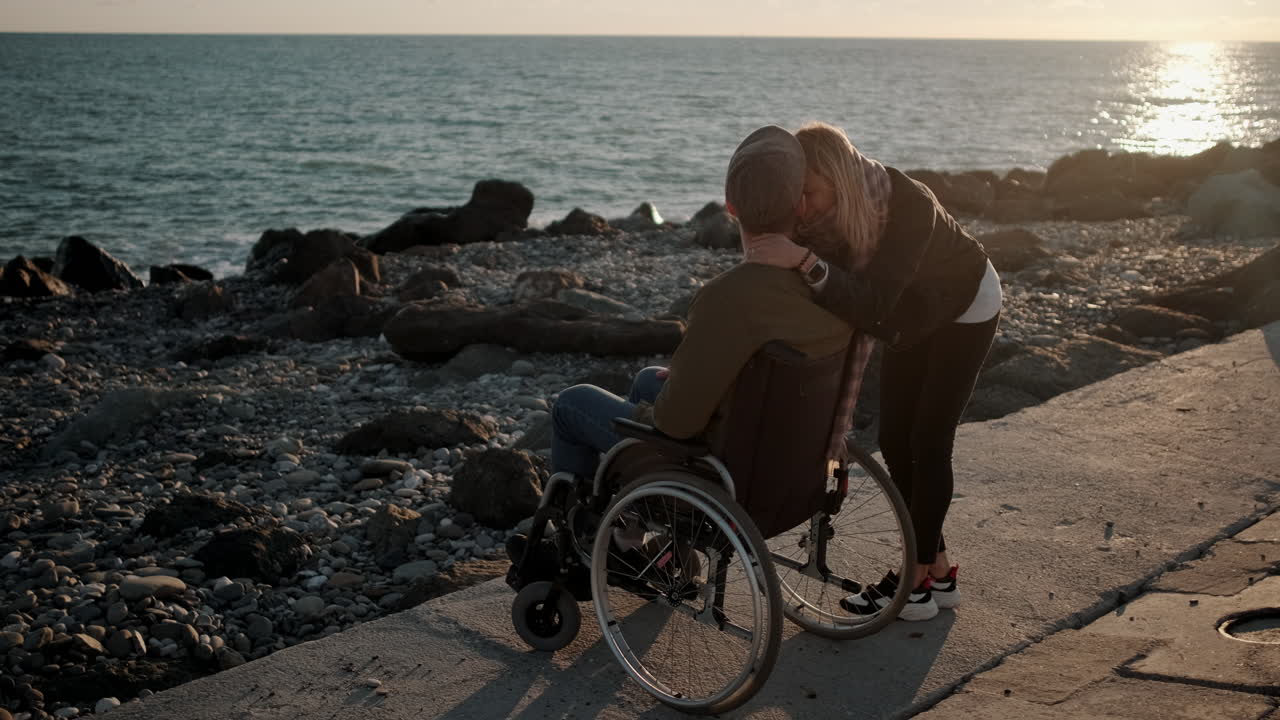 una pareja en la playa, abrazándose al atardecer.