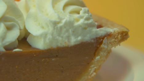 [Camera-Used:-Canon-C300]-Macro-shot,-pan-left,-pumpkin-pie-slice-loaded-with-fluffy-whipped-cream