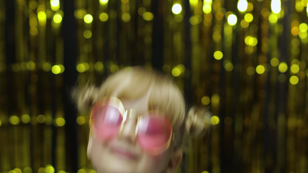 niño bailando, agitando las manos, haciendo tonterías. niña posando en el fondo con cortina de aluminio
