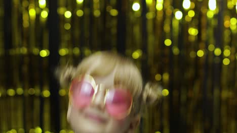 Child-kid-dancing,-waving-hands,-fooling-around.-Girl-posing-on-background-with-foil-curtain