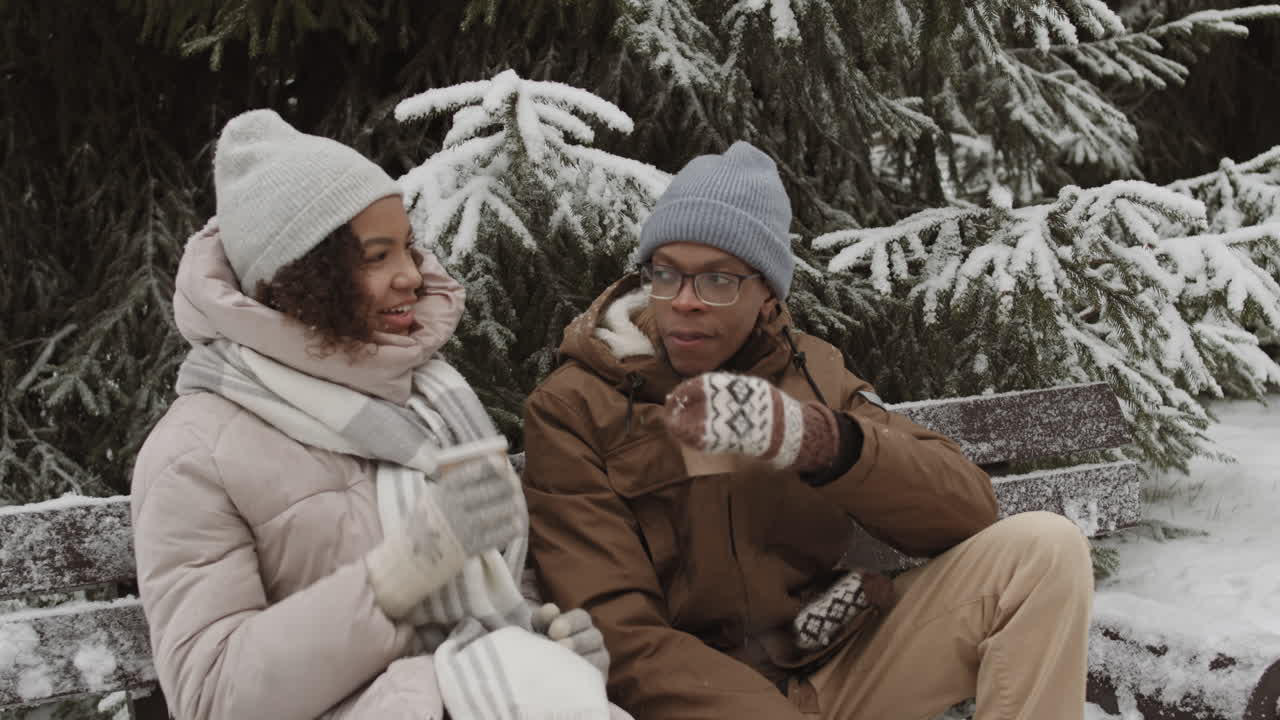 Casal desfrutando de café em parque nevado