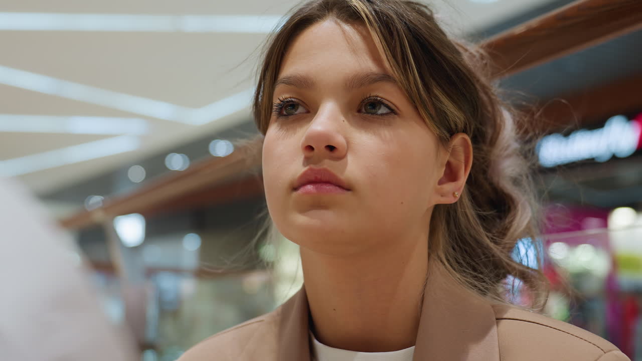 mujer caucásica con blazer informal concentrada en una obra de arte creativa, joven de ascendencia europea que estudia su obra de arte de cerca en un centro comercial con iluminación suave y postura reflexiva