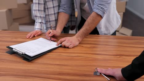 young couple signing a real estate purchase agreement and getting bunch of keys from new house. happy homeowners on relocation day. real estate and tenancy concept. loan mortgage for young family.