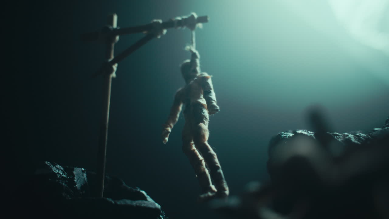 A miniature mummified doll hanging on the gallows at night