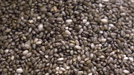 macro shot of chia seeds sliding down the side of a heaped pile as more is clearly being dropped on the top