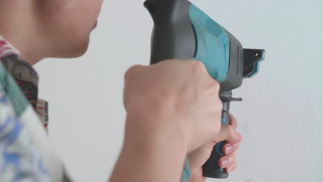 las manos del hombre usan un taladro eléctrico para perforar la pared