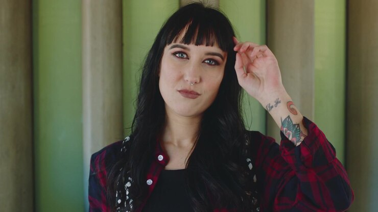 Mujer joven con cabello oscuro posando y ajustándose el cabello.