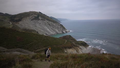 Hombre-Peregrino-Caminando-Sobre-Un-Acantilado-Oceánico-Nublado-Hasta-Deba-En-El-Camino-Del-Norte