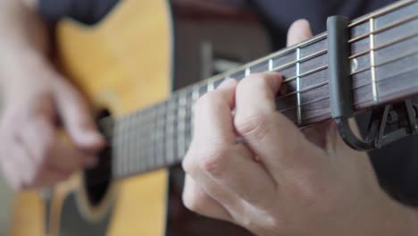 close-up, side view of a guitarist playing an acoustic steel-string guitar