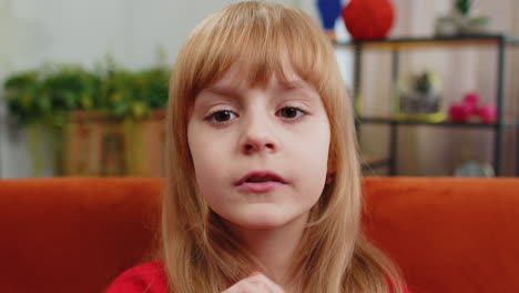 preteen child girl presses finger to lips makes silence hush sign do not tell gossip secret quiet