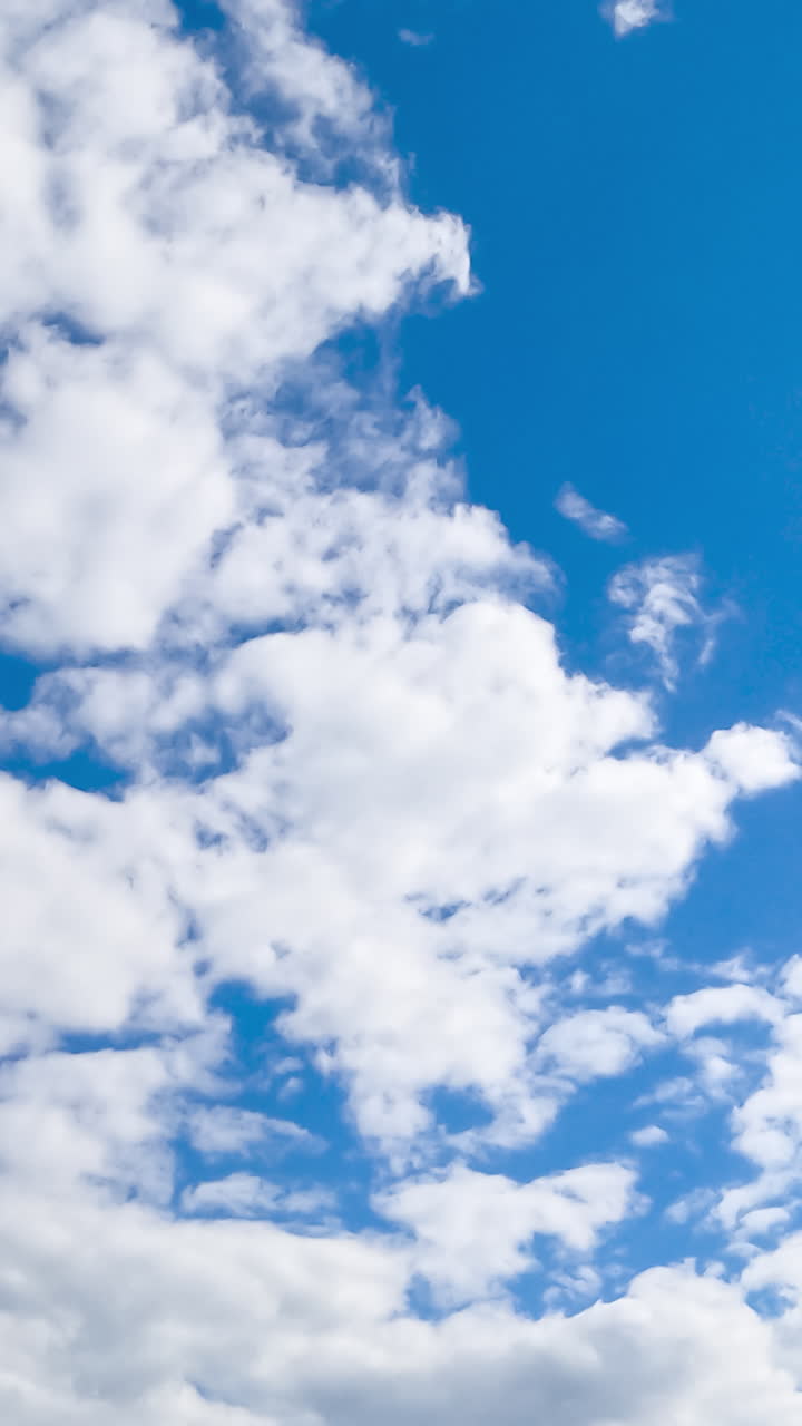 Soft white cloudscape moving by the azure horizon. Beautiful low angle view of sky on sunny day covering with light clouds. Timelapse. Vertical video