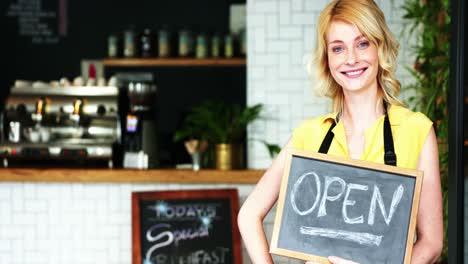 Portrait-of-waitress-standing-with-open-sign-board